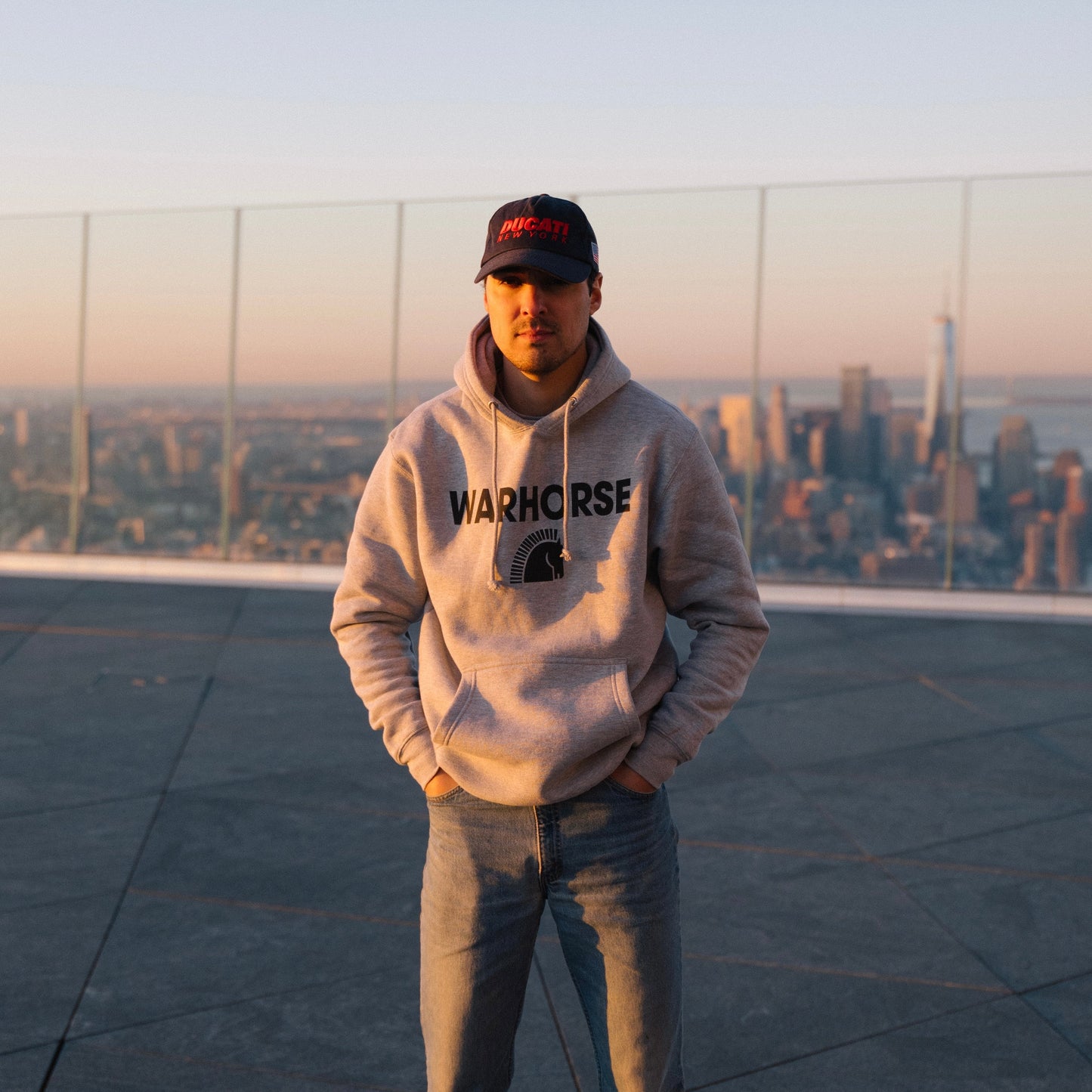 Person wearing a hoodie with 'Warhorse' branding on a rooftop with cityscape in the background