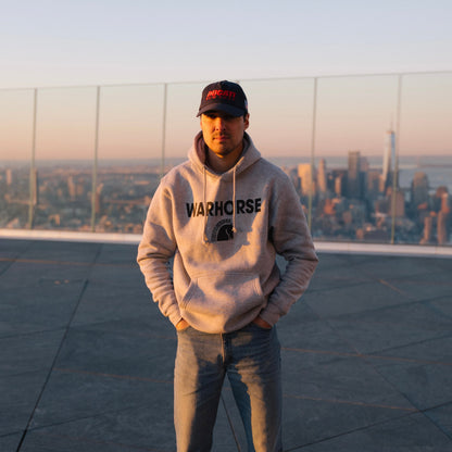 Person wearing a hoodie with 'Warhorse' branding on a rooftop with cityscape in the background